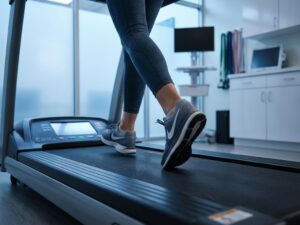 Atleet loopt op loopband in medische revalidatieomgeving met professionele begeleiding en veilige sportuitrusting