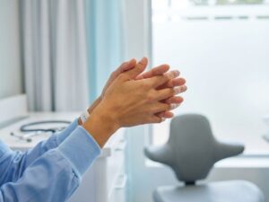 Gezonde handen strekken omhoog in medische omgeving met stethoscoop en ergonomische hulpmiddelen op achtergrond