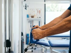 Sterke handen grijpen fysiotherapie-apparatuur in moderne revalidatiekliniek met medische hulpmiddelen op achtergrond