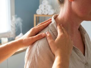 Handen masseren gespannen schouder en nek in serene spa-omgeving met zachte verlichting en handdoeken