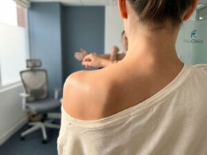 Ontspannen schouder en nek van achteren in warme verlichting, gezonde spieren in professionele kliniekomgeving