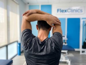 Persoon voert schouderoefening uit in moderne medische kliniek, toont gezonde spieren en gewrichtsmobiliteit