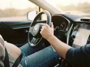 Handen aan het stuur van een auto, chirurgische litteken zichtbaar op been, comfortabele rijpositie in modern interieur
