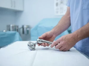 Titanium heupprothese in handen van arts op medische onderzoekstafel in steriele klinische omgeving